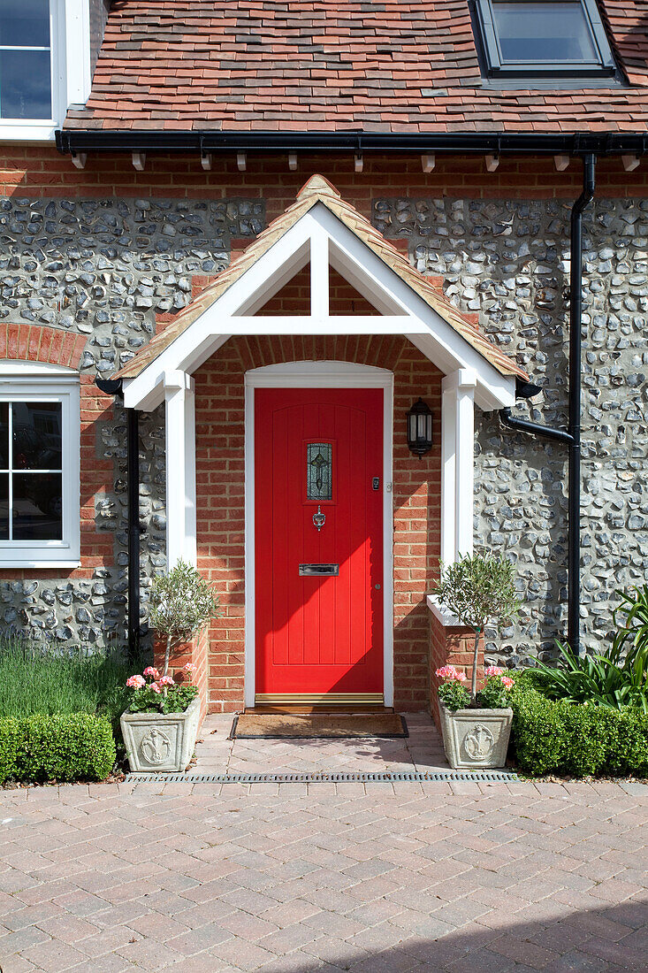 Rote Haustür eines Cottage aus Stein in Kent mit Abflussrohren in Kent, England, Vereinigtes Königreich