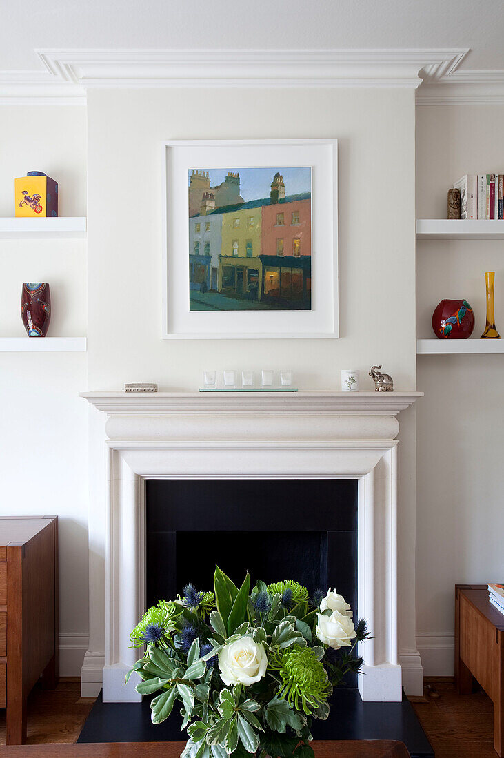 Moderne Kunst über dem Kamin mit Schnittblumen in einem modernen Einfamilienhaus in Herefordshire England UK