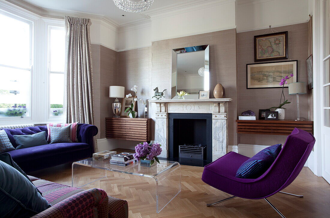 Lila Sessel und Sofa mit Plexiglas-Couchtisch im Wohnzimmer eines modernen Londoner Stadthauses, England, UK