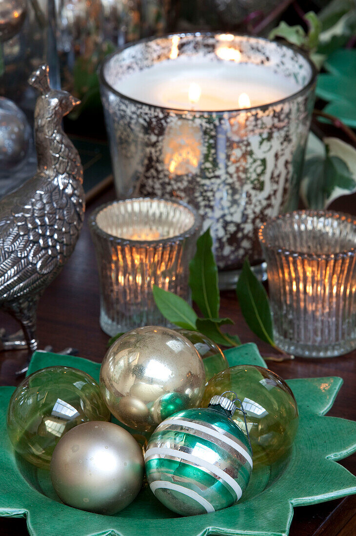 Beleuchtete Kerzen und Weihnachtskugeln mit Silberbesteck auf dem Esstisch in einem Haus in London, UK