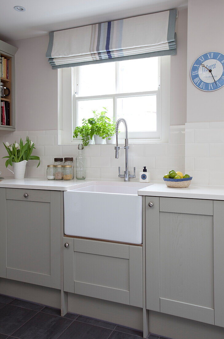 Pastel fitted units with butler sink in kitchen of London townhouse, England, UK
