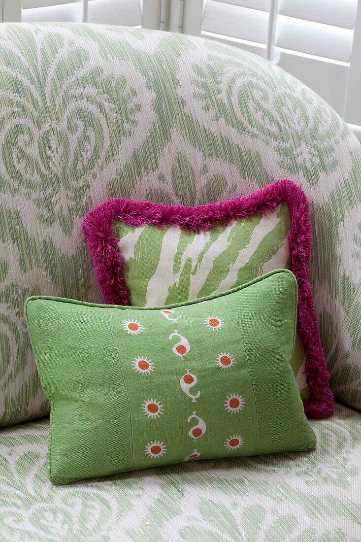 Green cushions on patterned sofa in London townhouse, England, UK