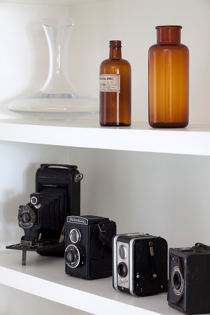 Vintage-Kameras und Flaschen auf einem Regal in einem Londoner Stadthaus, England, UK