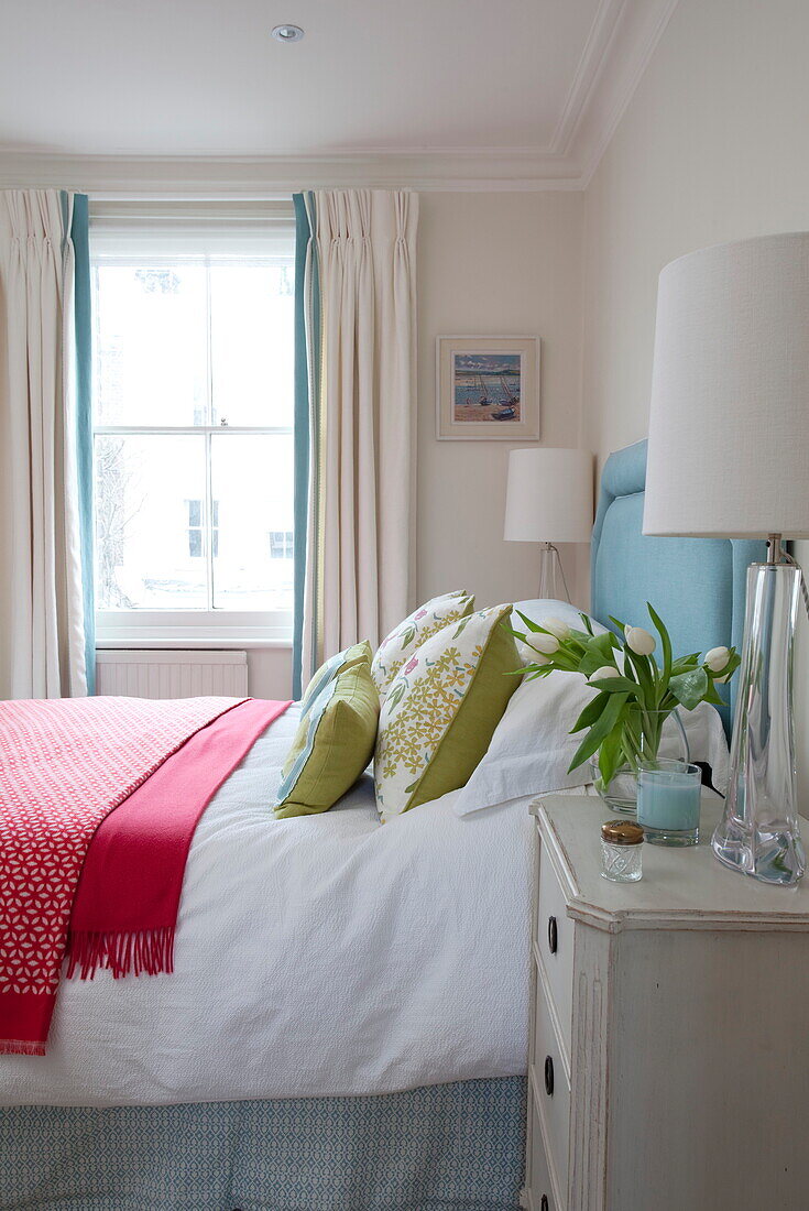 Red blankets in bedroom with sash window in London townhouse, England, UK