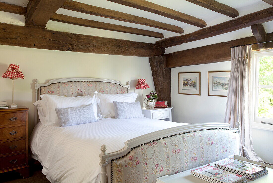 Gepolstertes Bett in niedrigem Balkenraum eines Bauernhauses in Maidstone, Kent, England, UK