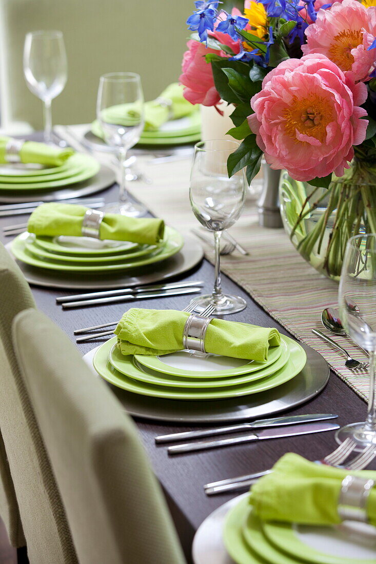 Limonengrüne Teller und Servietten auf einem Esstisch in einem modernen Londoner Stadthaus, England, UK