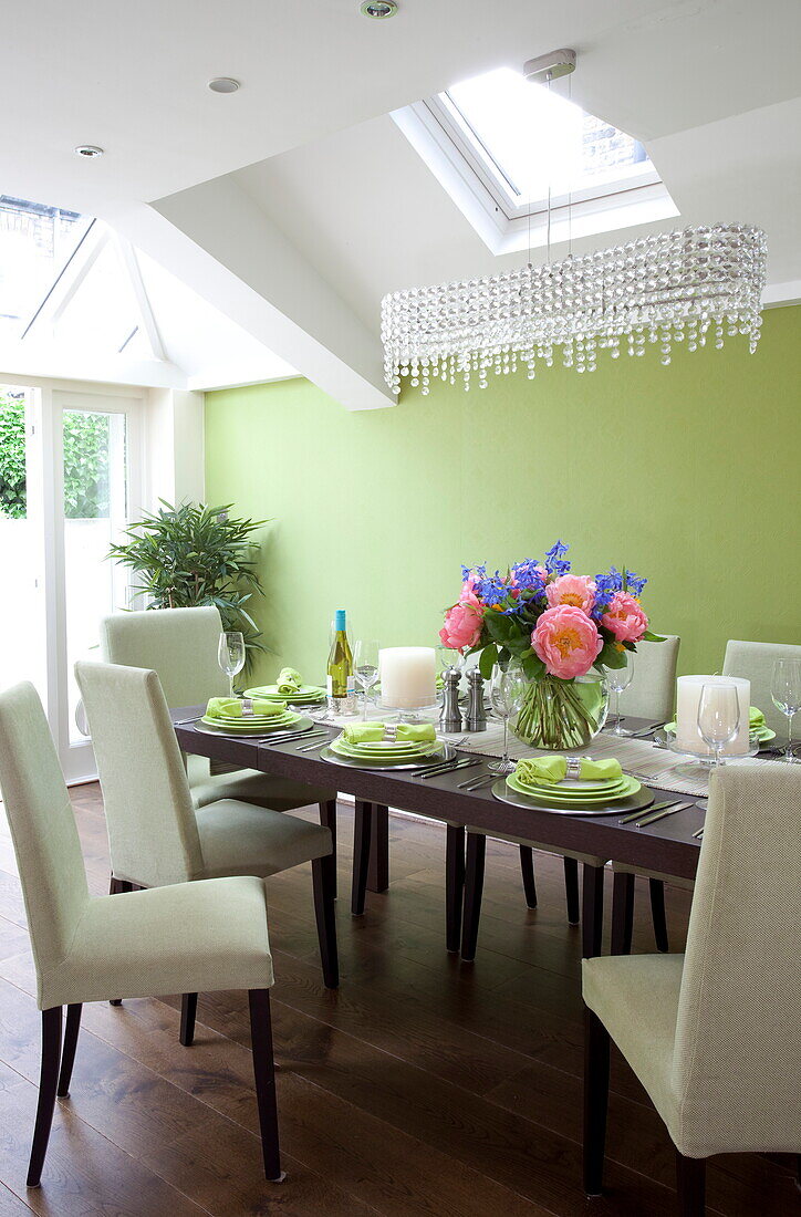 Floral centrepiece on dining table below skylight in contemporary London townhouse, England, UK