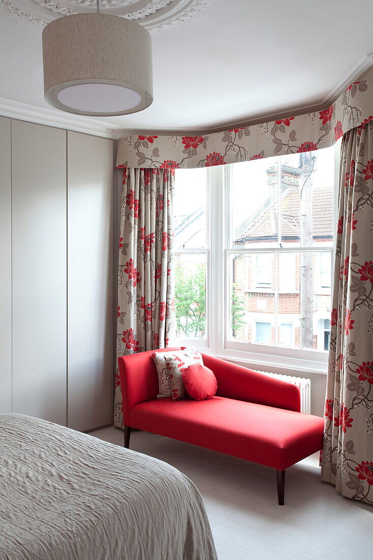 Rote Chaiselongue am Schlafzimmerfenster mit Vorhängen in einem modernen Londoner Stadthaus, England, Vereinigtes Königreich