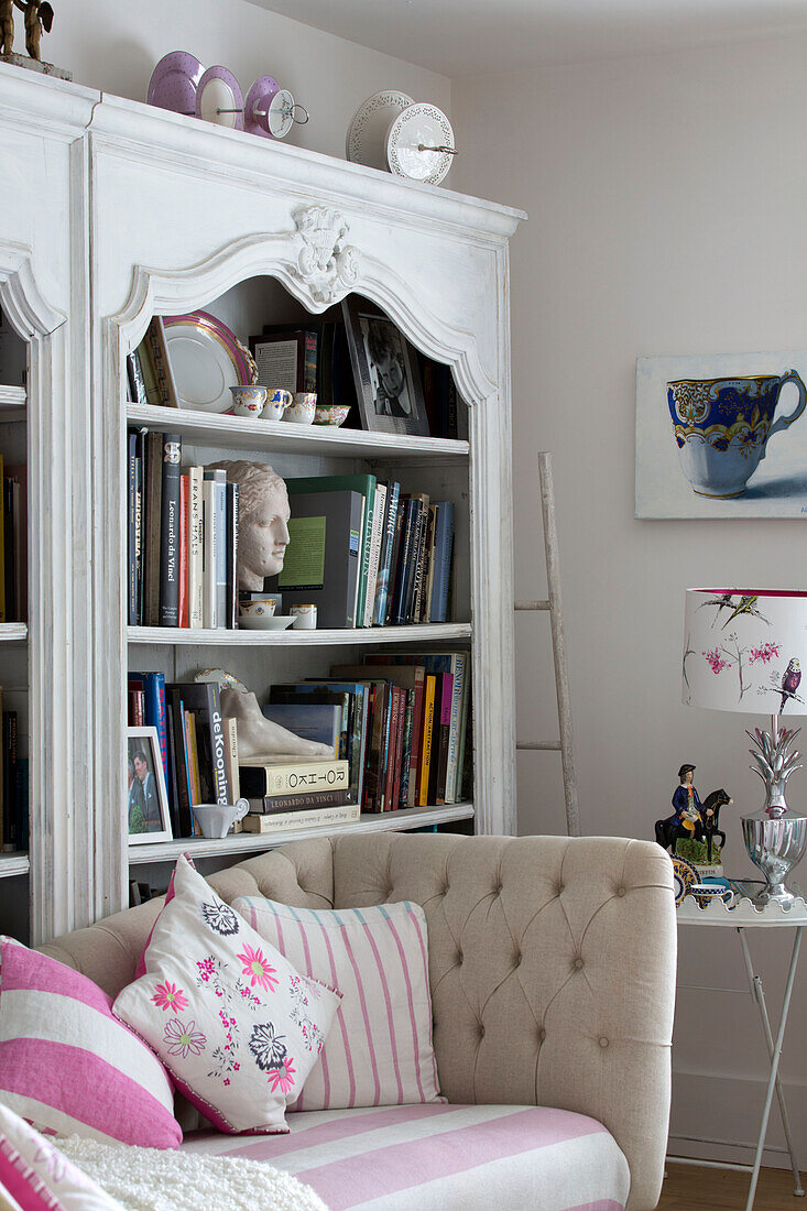 Kissen auf gepolstertem Sofa mit Bücherregal im Wohnzimmer eines Hauses in Dulwich, London, England, UK