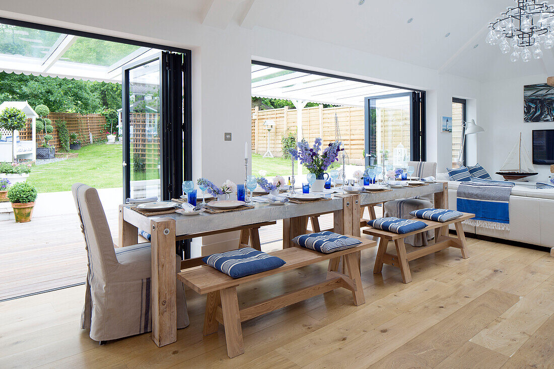 Langer Esstisch im offenen Wohnbereich mit Doppelflügeltüren mit Blick auf den Garten in einem Haus in Dulwich, London, UK