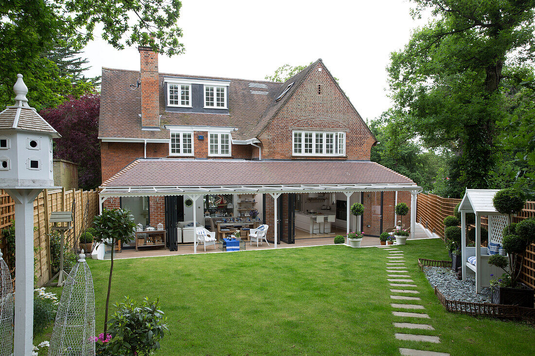 Blick auf die Rückseite des Hauses mit dem angelegten Garten, der die Erweiterung und die Veranda zum offenen Wohnbereich zeigt