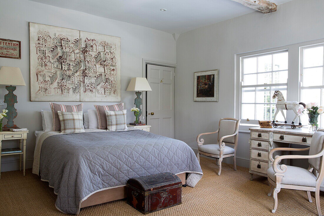 Blau-weiß gesteppte Bettdecke und Kunstwerke im Schlafzimmer eines historischen Landhauses in Sussex, England, Vereinigtes Königreich