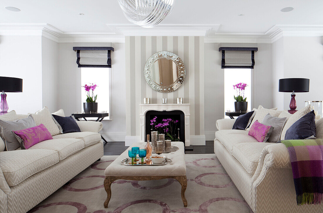 Pair of white sofas with cushions in living room of contemporary Surrey country home England UK