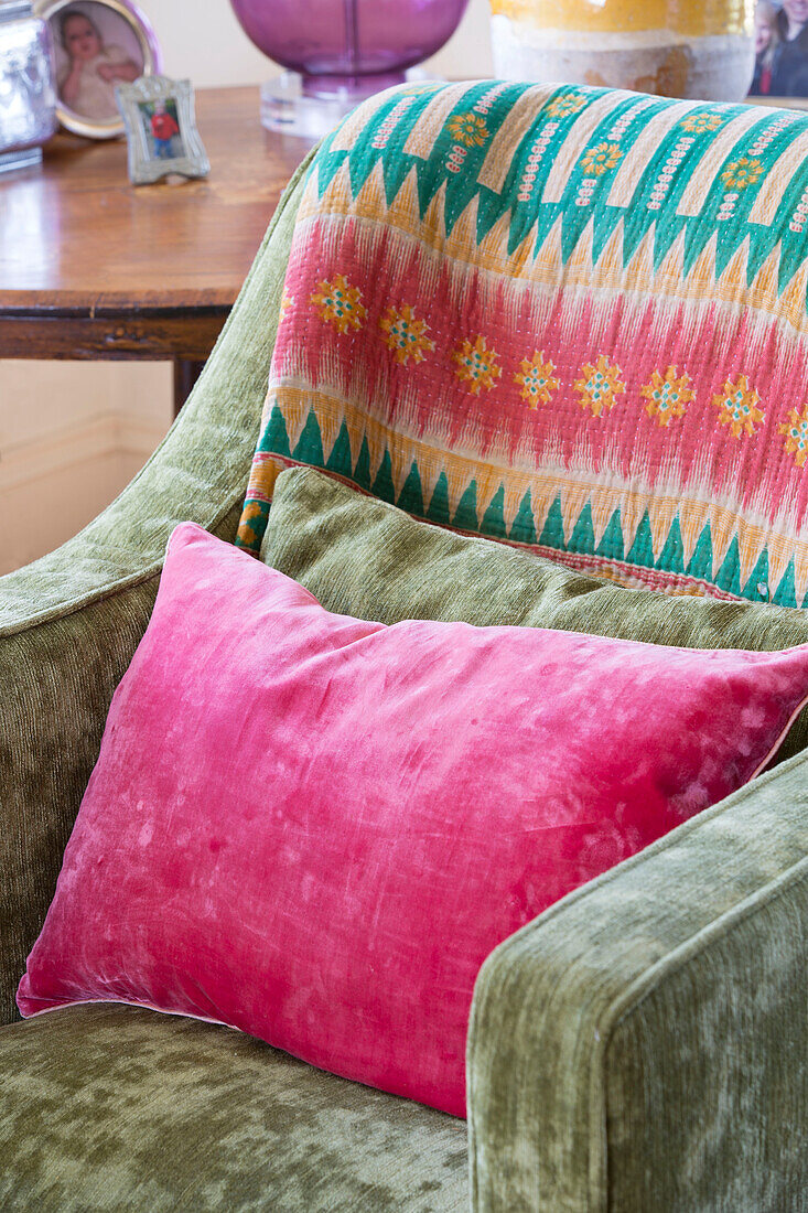 Bright pink cushion on brushed velvet armchair in Sussex home England UK