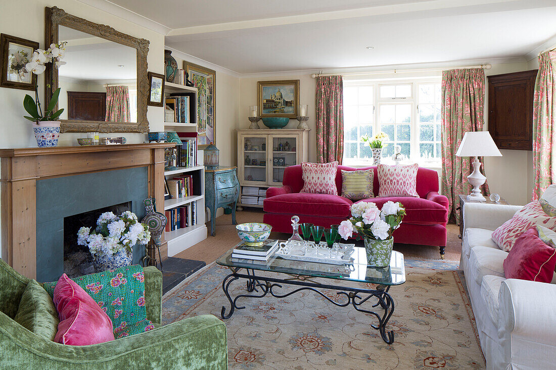 Rosa und weiße Sofas mit grünem Sessel und Couchtisch mit Glasplatte im Wohnzimmer eines Hauses in Sussex, England, UK