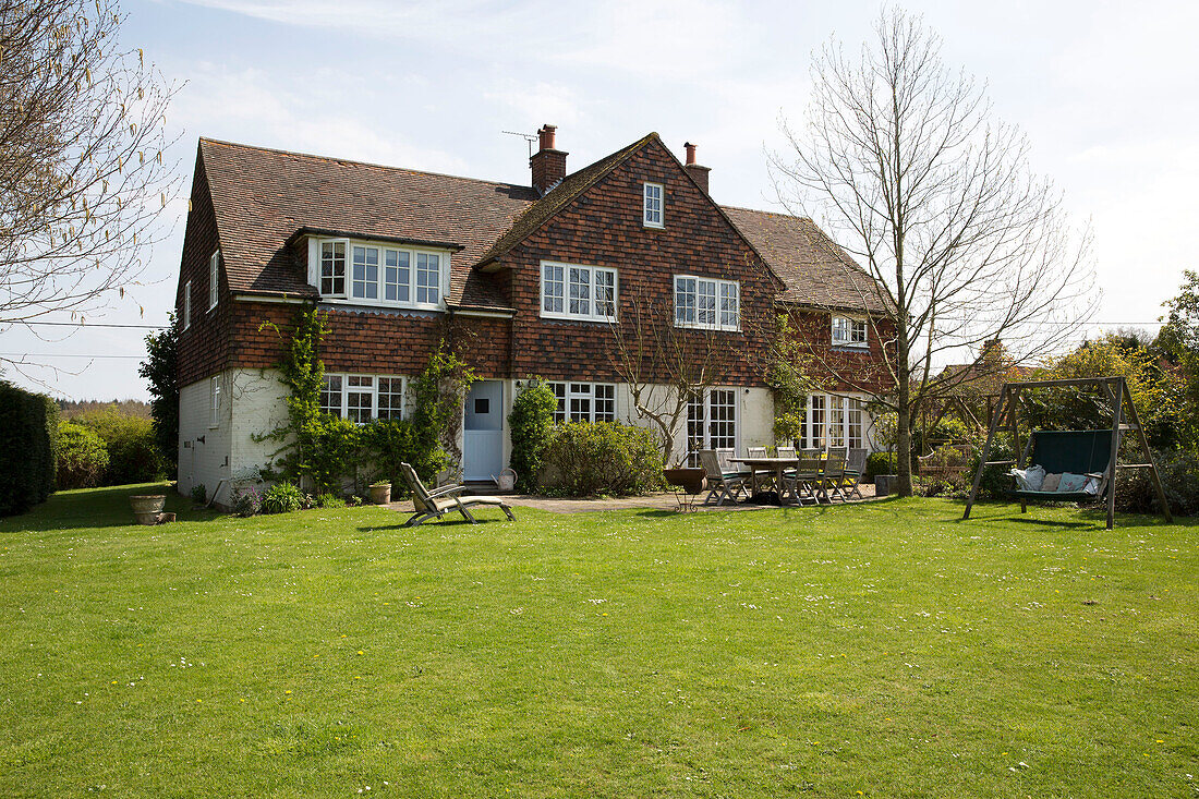 Gartenmöbel auf einer Terrasse im Garten eines freistehenden Hauses in Sussex, England UK