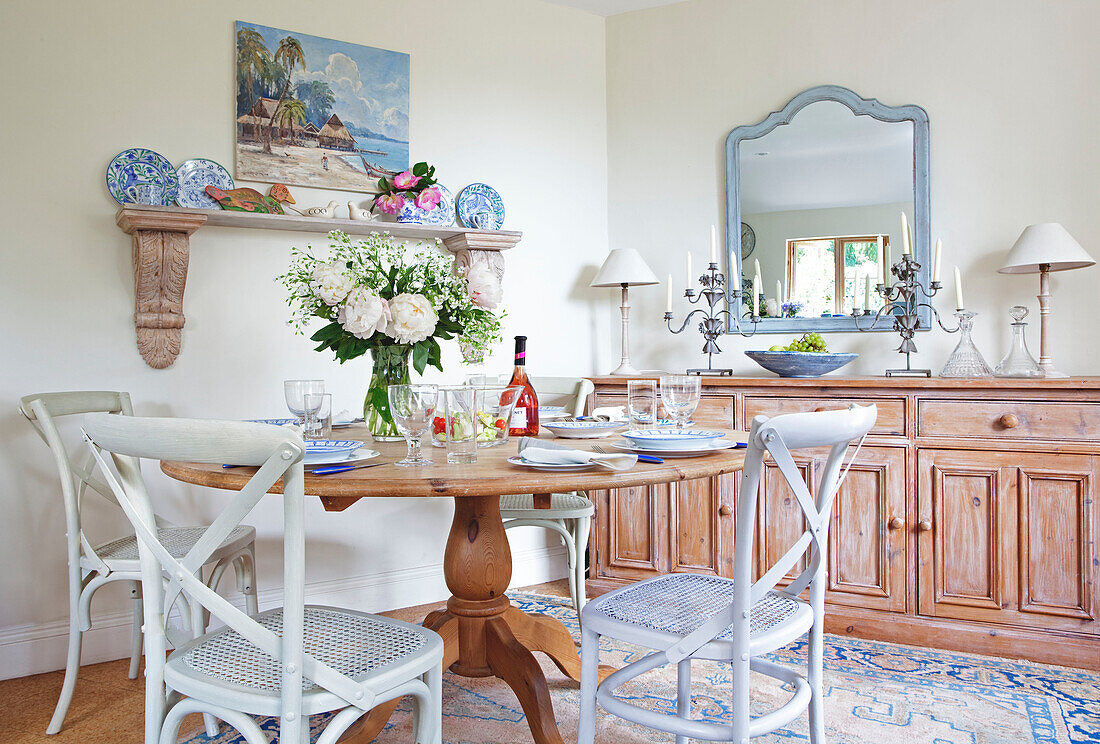 Painted wicker chairs at wooden dining table in Sussex cottage, England, UK