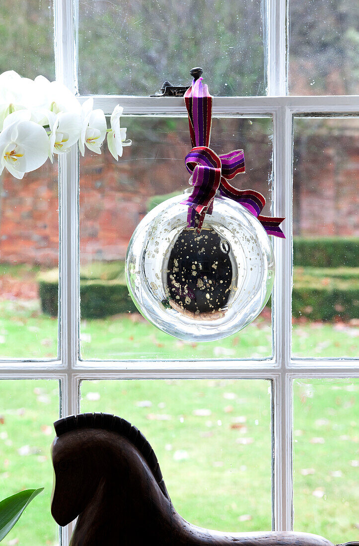Glaskugel am Fenster eines Bauernhauses in Surrey mit Orchidee und Pferdestatue, England, Vereinigtes Königreich