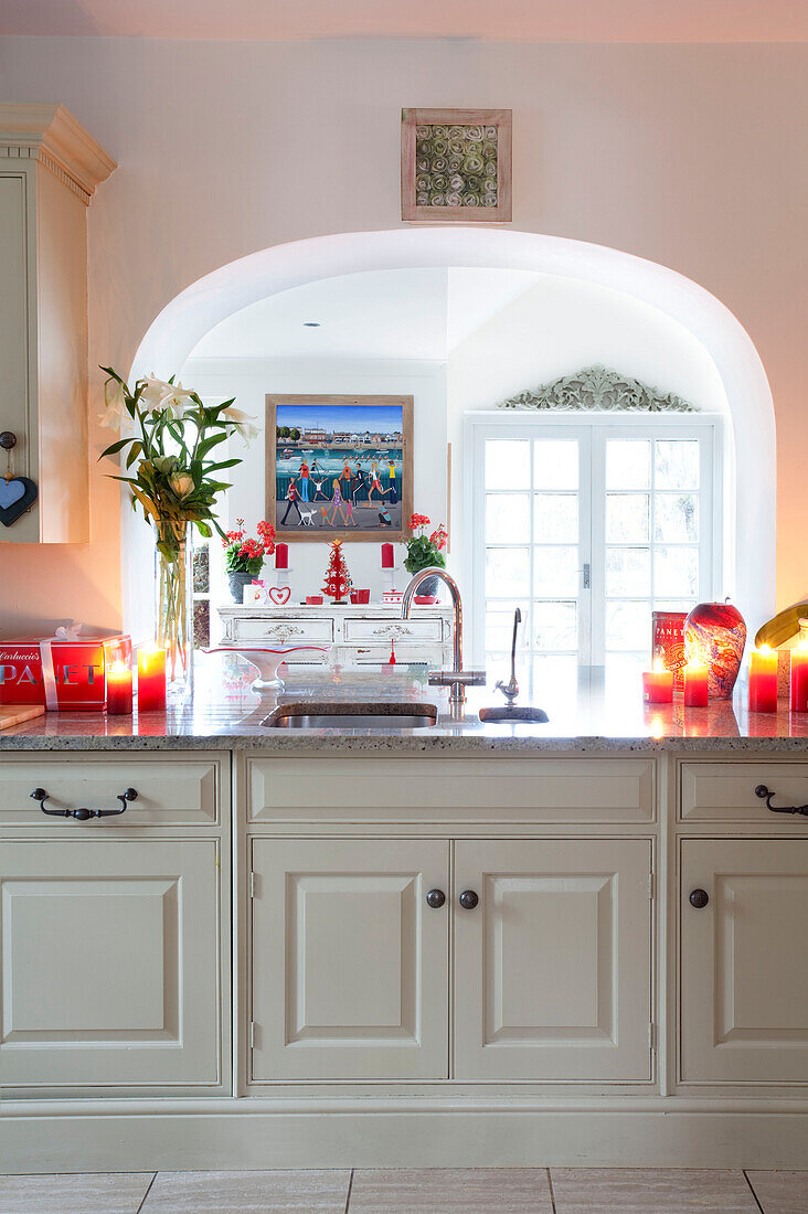 Arched kitchen detail in Surrey farmhouse with glowing candles on marble worktop, England, UK