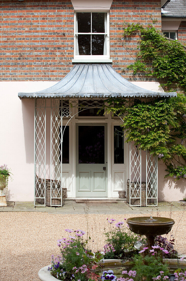 Überdachte Veranda und Wasserbrunnen am Eingang eines Landhauses in Sussex, England, Vereinigtes Königreich