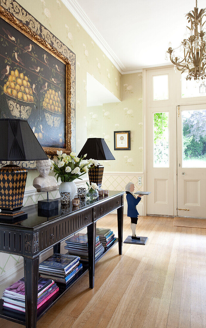 Matching lampshades and artwork with console in hallway of Sussex country house, England, UK