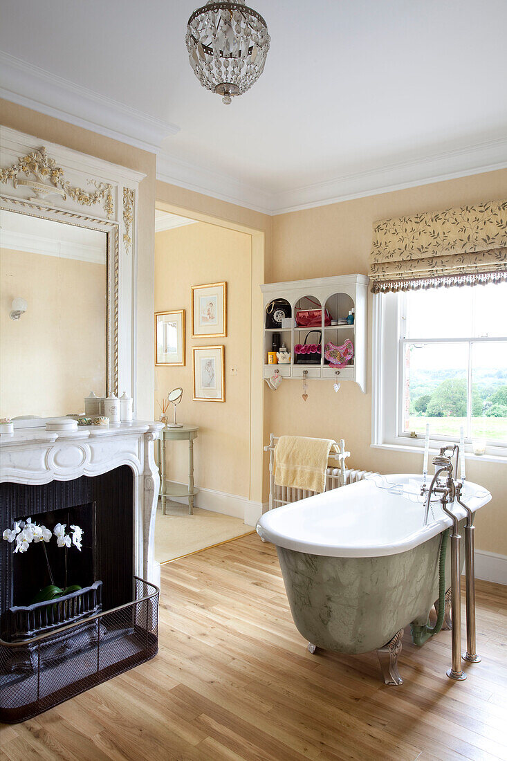 Freistehende Badewanne aus Silbermetallic mit Marmorkamin und Spiegel in einem Landhaus in Sussex, England, UK