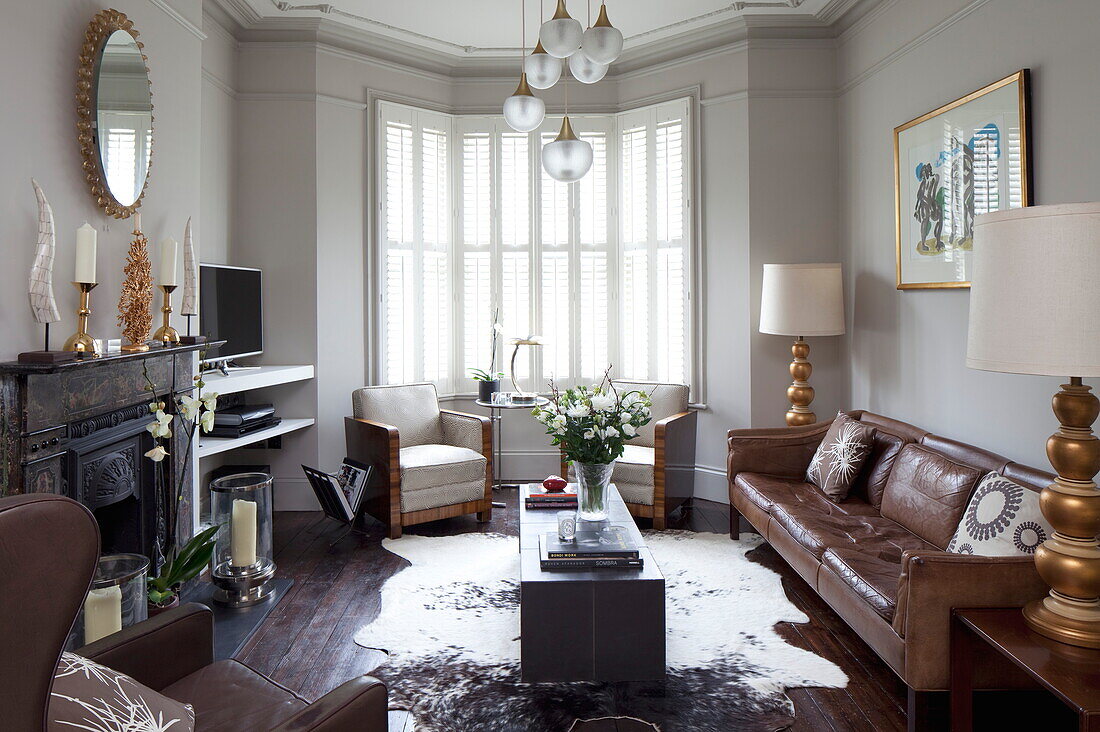 Braunes Ledersofa mit einem Paar Vintage-Sesseln im Wohnzimmer eines Londoner Stadthauses, England, Vereinigtes Königreich