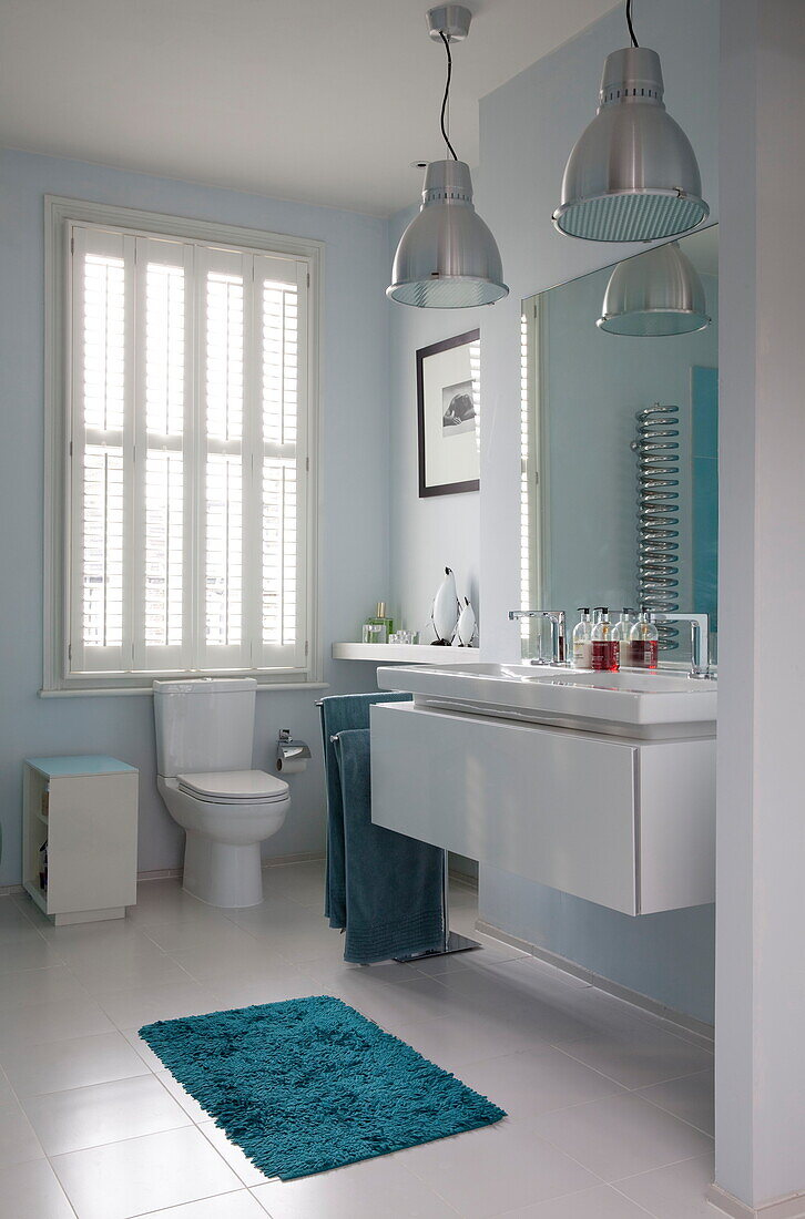 Turquoise bath mat and chrome pendant lights in bathroom of London townhouse, England, UK