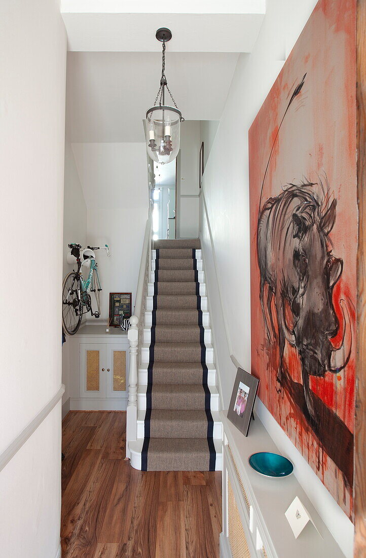 Kunstwerk im Flur mit Teppichtreppe und Fahrrad in einem Londoner Haus, England, UK