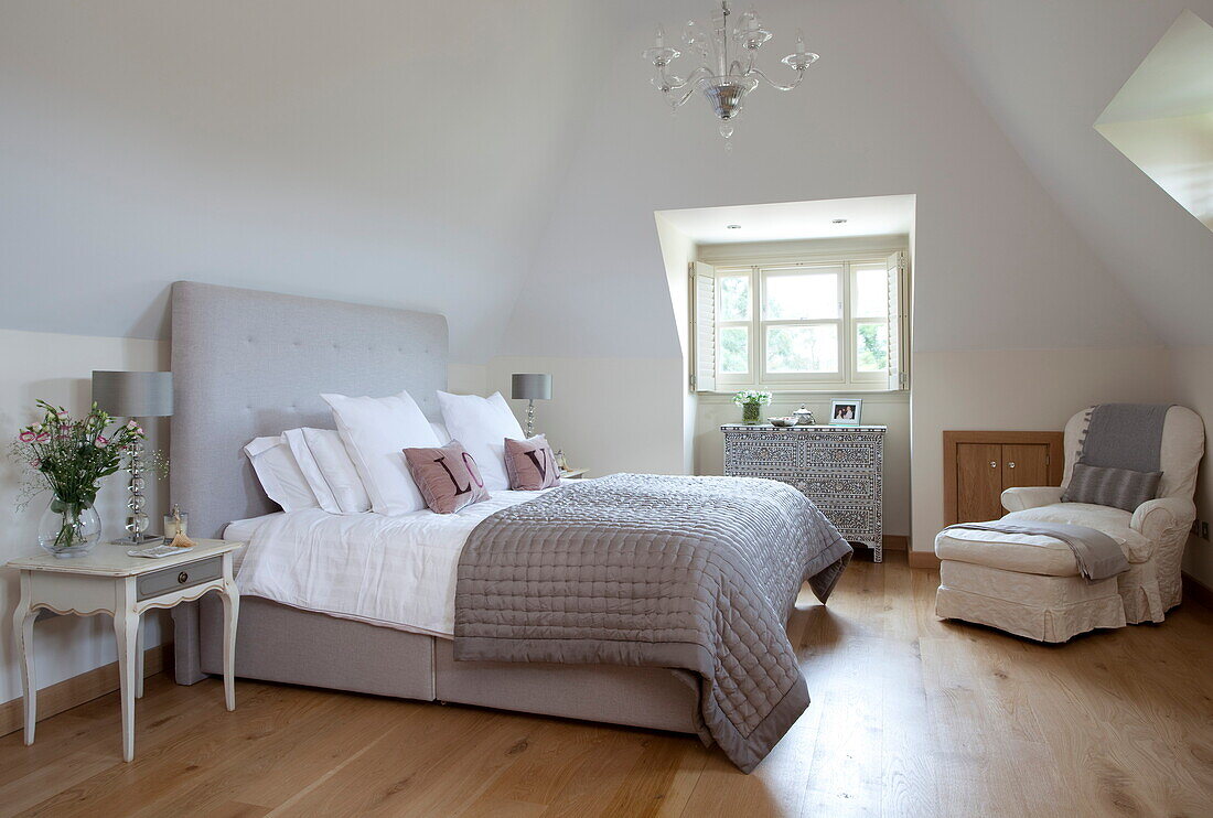 Hellgraue Bettdecke und Kopfteil auf einem Bett in einem Zimmer mit Holzboden, Haus in Kent, England, Vereinigtes Königreich