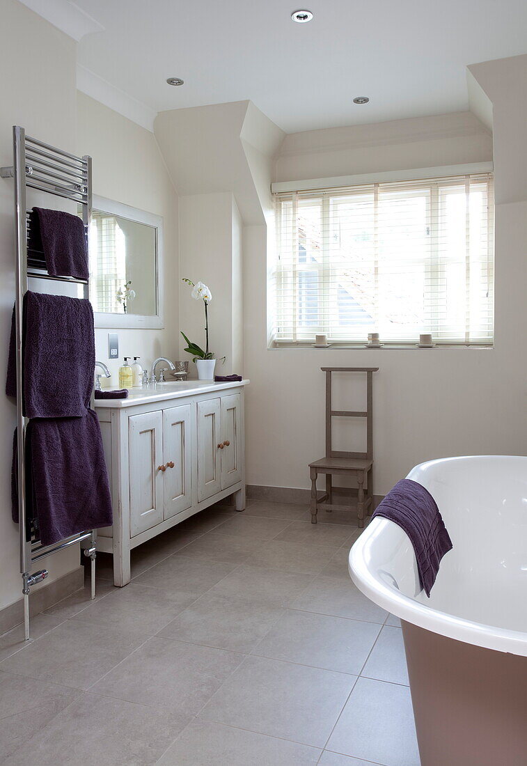 Lila Handtücher und freistehende Badewanne mit Waschtisch in einem Haus in Kent, England, UK