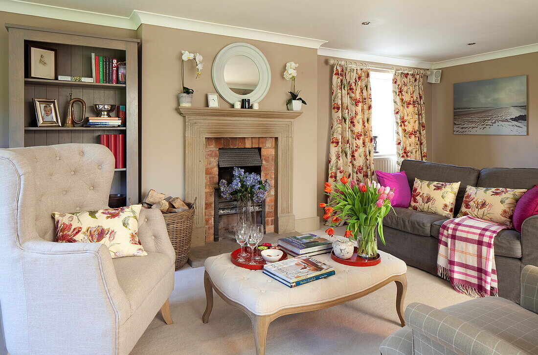 Cut tulips on ottoman footstool with large armchair in Staffordshire farmhouse living room England UK
