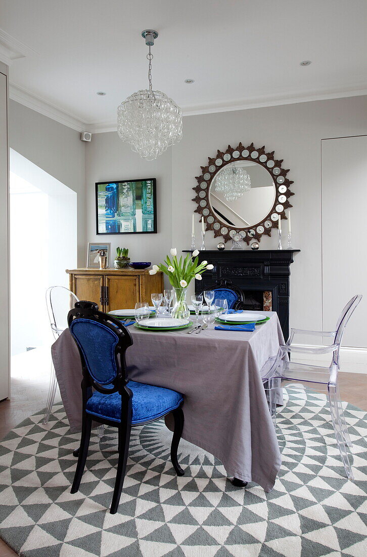 Blue and Ghost dining chairs at table on patterned rug in London townhouse England UK