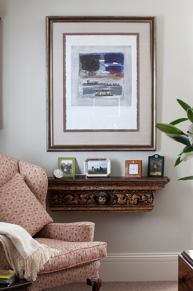 Kunstwerk über einem wandmontierten Regal mit Sessel im Wohnzimmer eines Familienhauses in Kent, England, UK