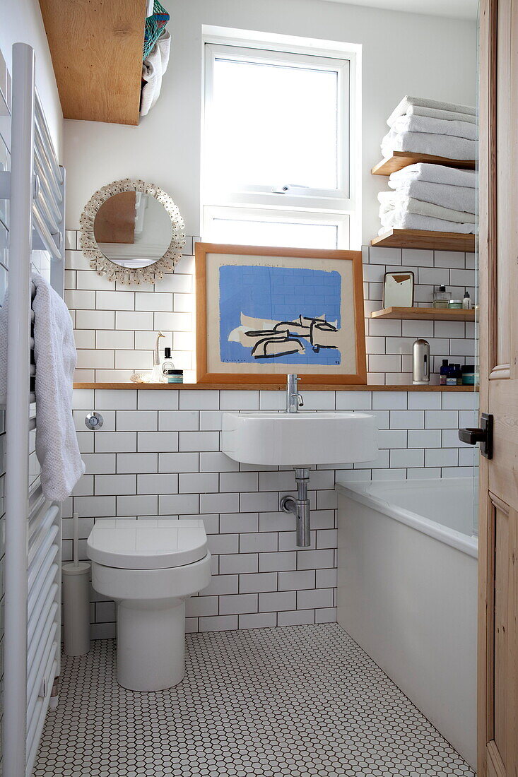 Weiß gefliestes Badezimmer mit Holzregalen im Badezimmer eines Einfamilienhauses in Kent, England, Vereinigtes Königreich