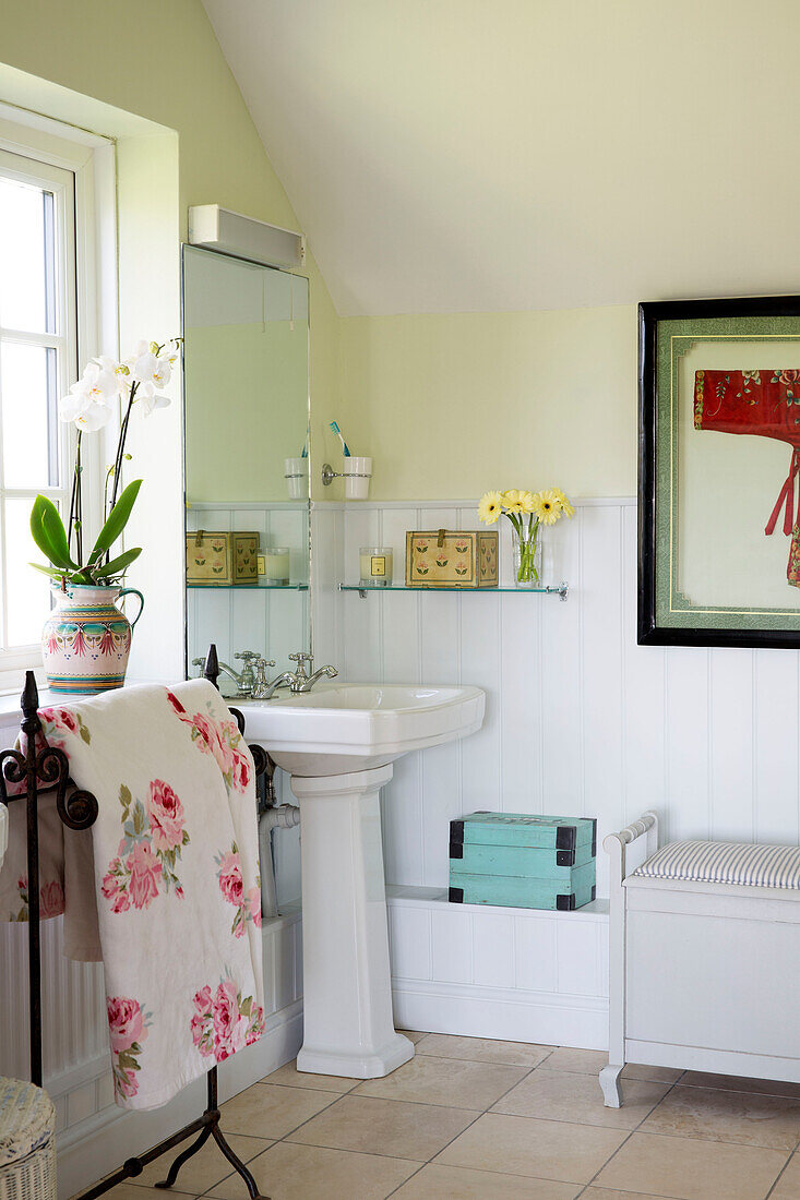 Floral bath towel beside pedestal basin in tiled bathroom of Sussex home England UK