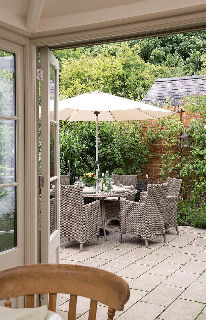 Sonnenschirm mit Gartenstühlen auf der Veranda eines Hauses in den Sussex Downs, England, UK