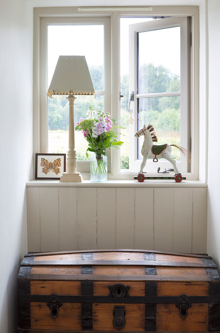 Toy horse and lamp on windowsill above wooden travelling chest in Sussex Downs home, England, UK