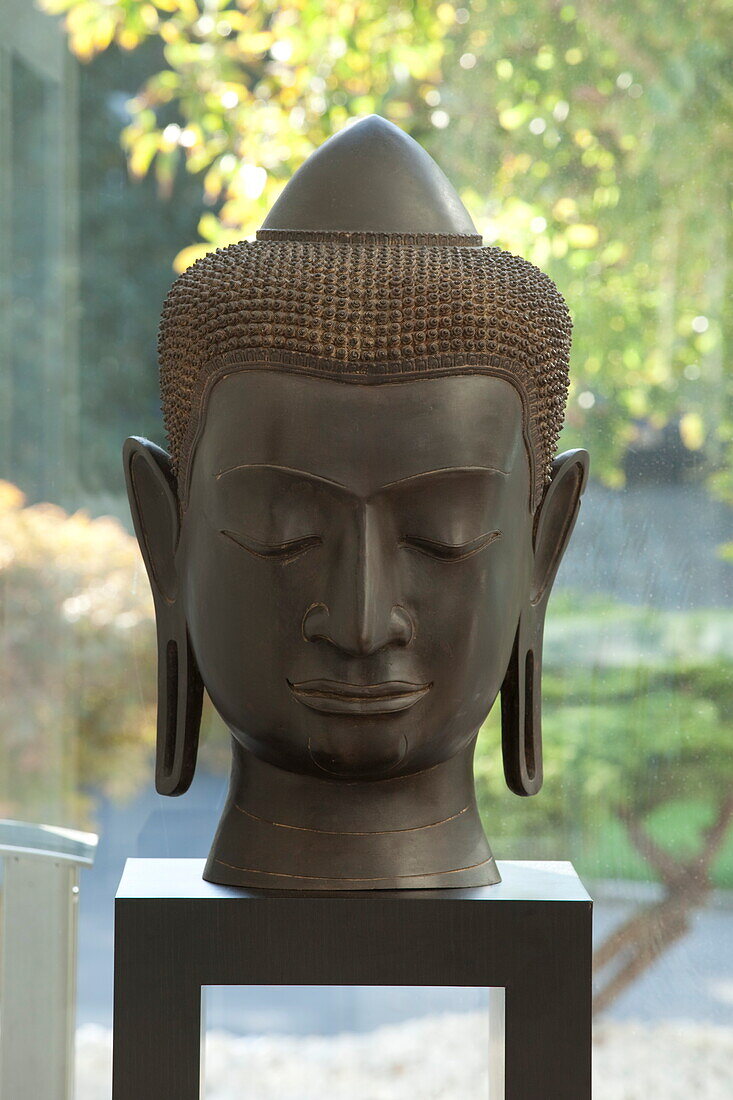 Buddha statue in window of contemporary new build, Kingston upon Thames, England, UK