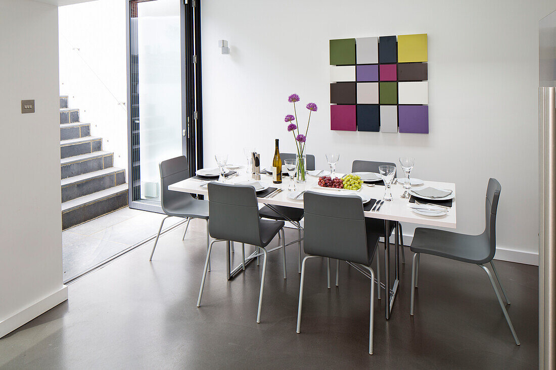 Graue Esszimmerstühle am Tisch mit modernen Kunstwerken in einem modernen Haus in Brighton, East Sussex, England, UK
