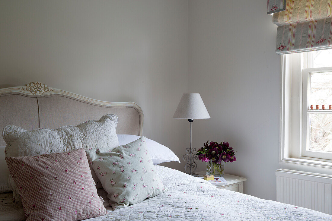 Gingham- und Blumenkissen auf einem Doppelbett in einem Haus in Burwash, East Sussex, England, Vereinigtes Königreich