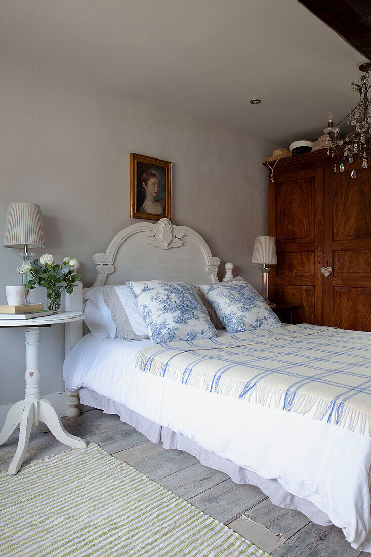 Toile-de-Jouy-Kissen und karierter Bezug auf einem Bett mit geschnittenen Rosen neben einem Haus in West Sussex, England, Vereinigtes Königreich