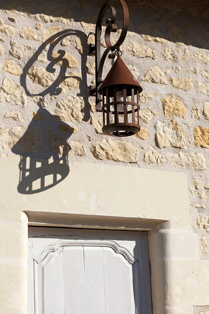 Wrought iron lantern above doorway of stone farmhouse exterior in the Loire, France