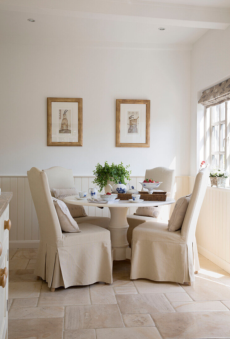 Cremefarbene Stühle mit Schlupfbezügen am Tisch in einem Haus in West Mailing, Kent, England, UK