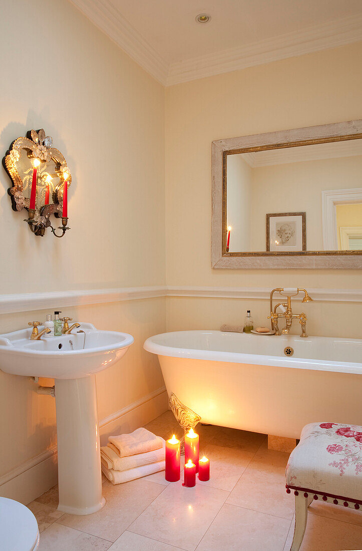 Beleuchtete Kerzen und freistehende Badewanne mit rechteckigem Spiegel in einem Haus in West Sussex, England, Vereinigtes Königreich
