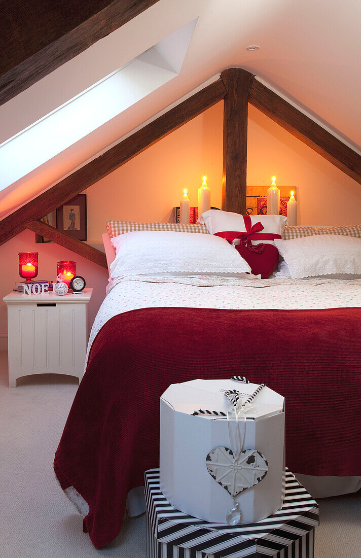 Rote Decke auf Doppelbett mit brennenden Kerzen und Geschenkboxen in West Sussex Dachgeschoss Schlafzimmer England UK