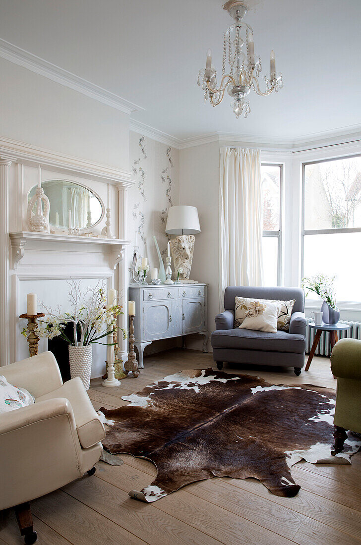 Cremeweiße und graue Sessel mit Tierfellteppich im Wohnzimmer eines Londoner Stadthauses, England, UK