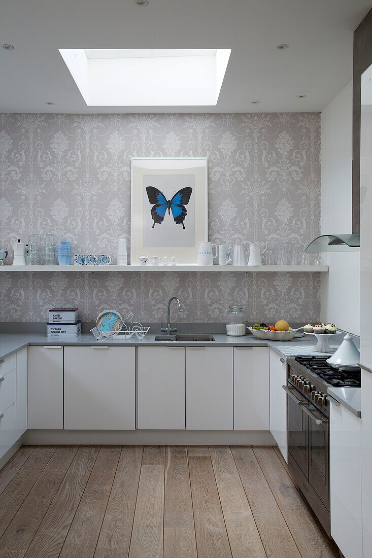 Butterfly print under skylight in white fitted kitchen with wooden floor, London townhouse, England, UK