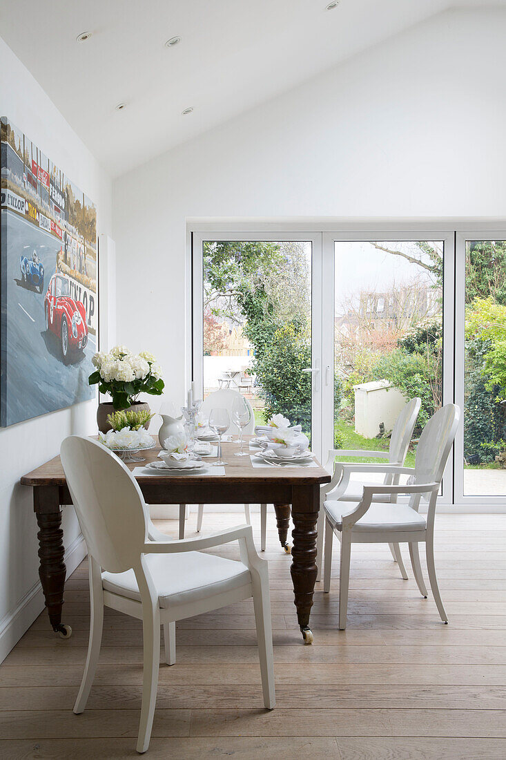Hölzerner Esstisch mit weißen Stühlen und Leinwand in einem Londoner Stadthaus, England, UK