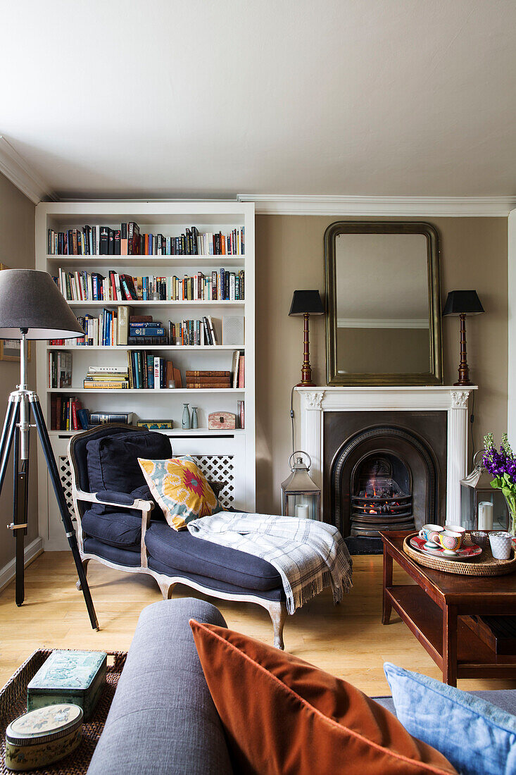 Lehnsessel mit Bücherregal am Kamin in einem modernen Londoner Haus, England, UK